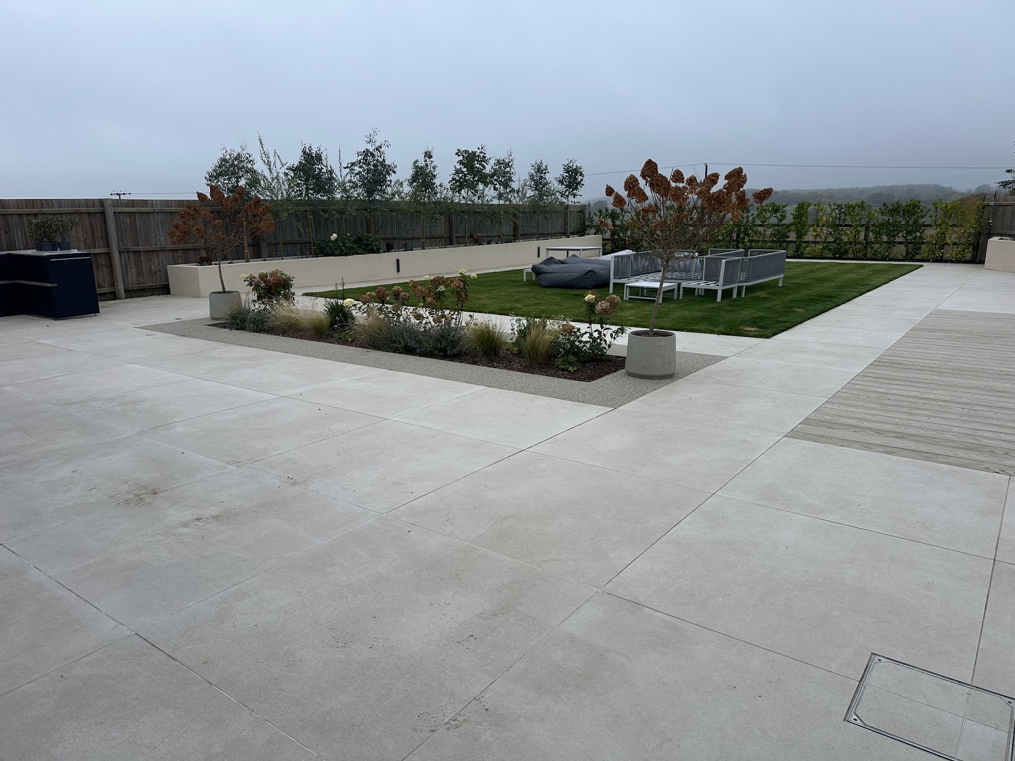 A large, freshly cleaned pale-stone patio with the garden beyond