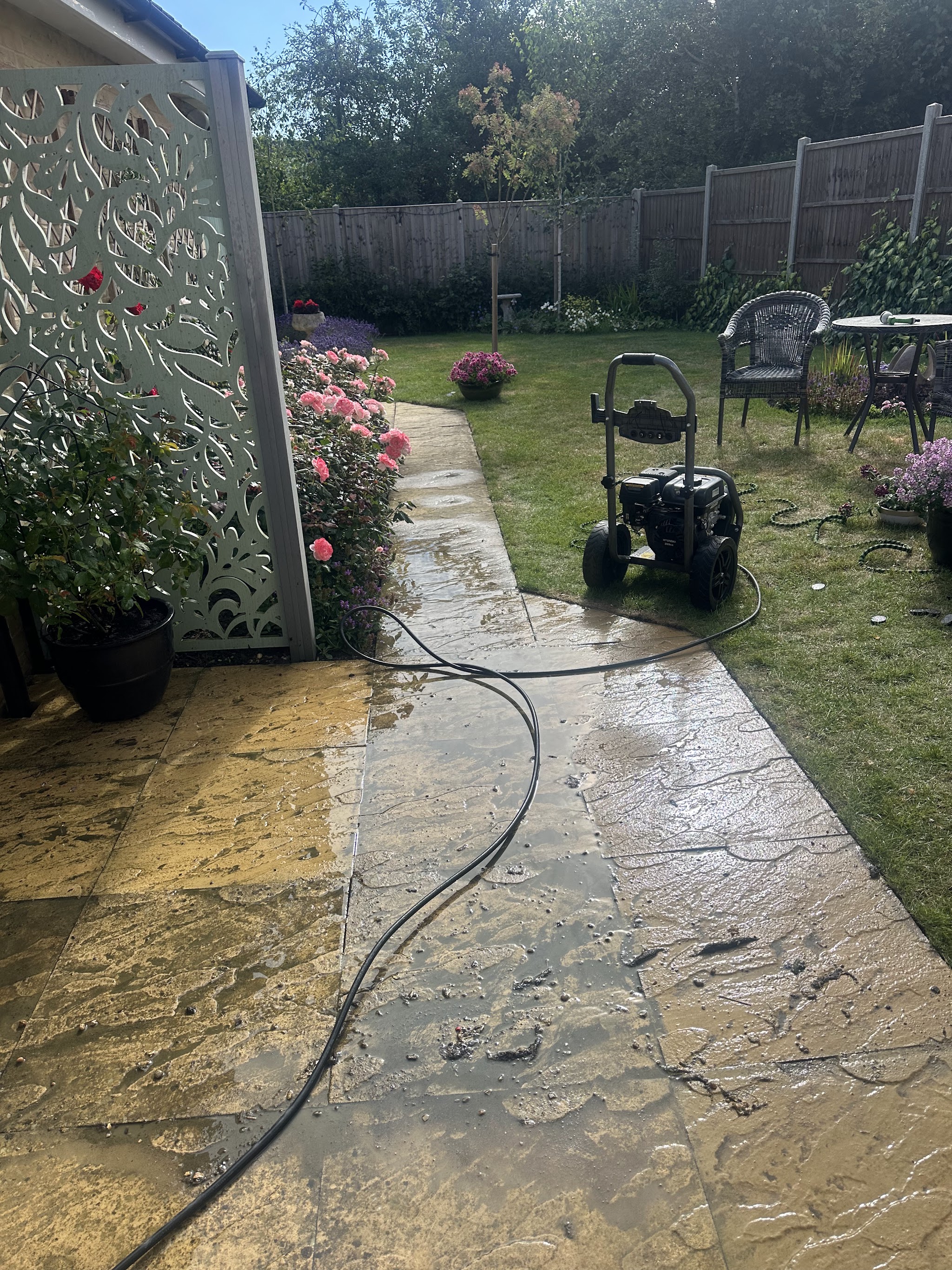 Patio mid-clean with a pressure washer on the lawn