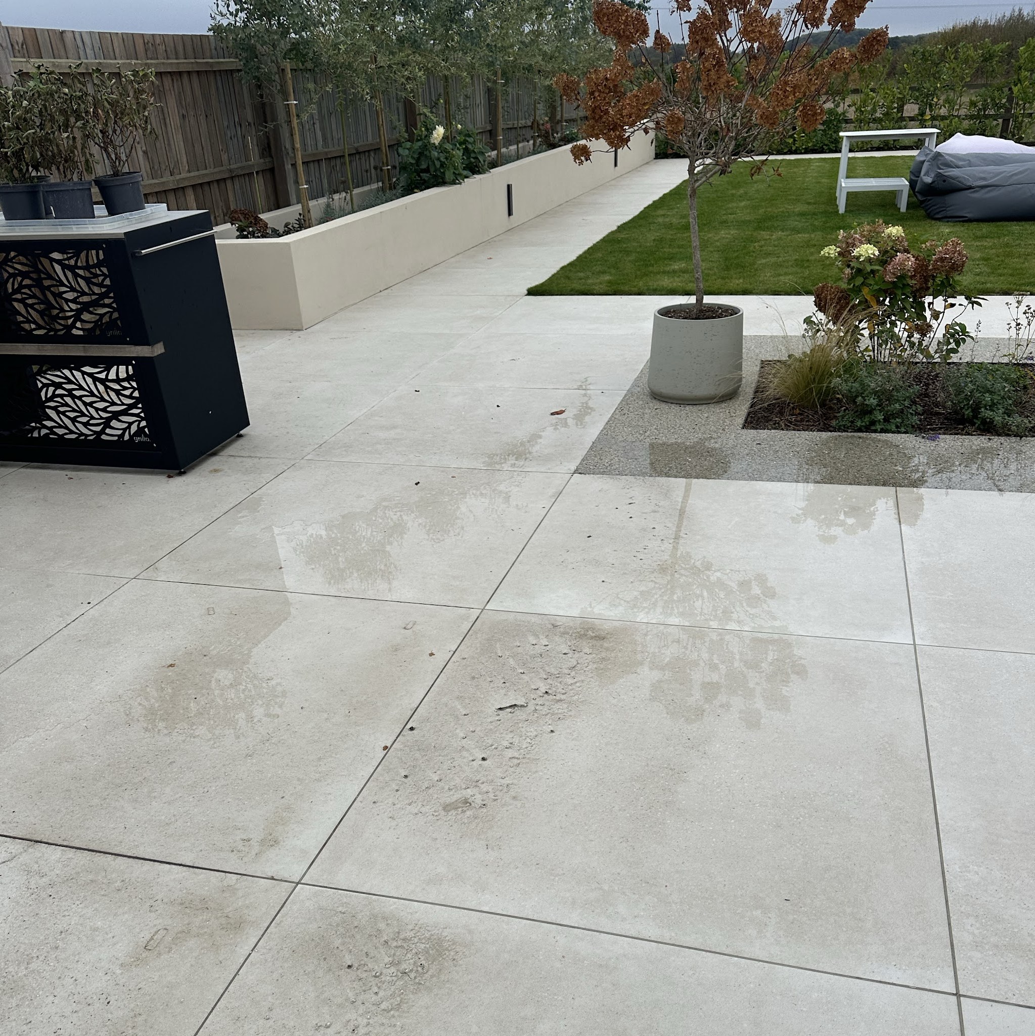Clean pale patio tiles beside a lawn